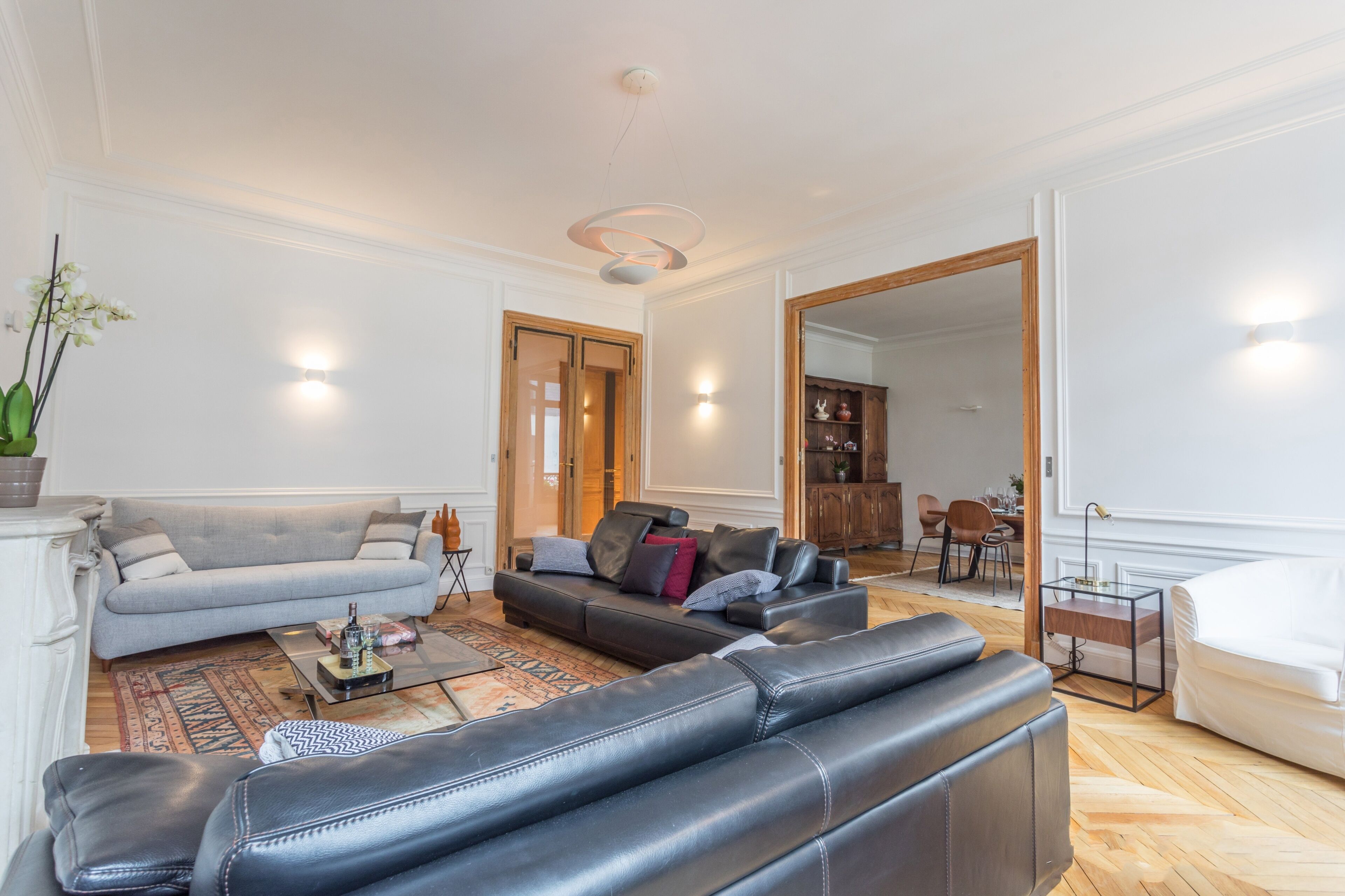 A living room with a sofa, a coffee table, and a dining area with chairs and a table.