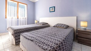 Quarto com duas camas, mesa de cabeceira com abajur, quadro pendurado na parede e janela com cortinas.