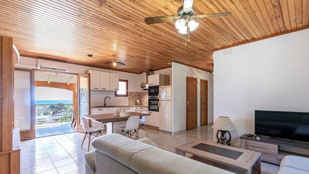 Uma sala de estar moderna com sofá, TV e área de refeições com mesa e cadeiras.