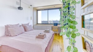 A bedroom with a bed, a desk, and a window with a view. - L'Atelier de Sèvres - 2 places de parking (Boulogne-Billancourt)