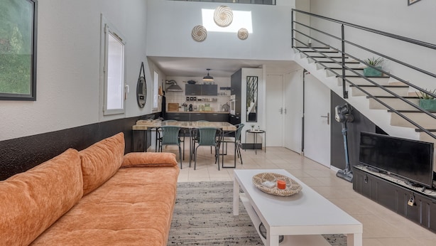 Un apartamento moderno con sala de estar, comedor, cocina y una escalera que conduce a un piso superior.