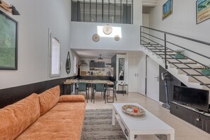 A modern apartment with a living room, dining area, kitchen, and a staircase leading to an upper floor. - La Baie d'Alon - Appt climatisé proche plage (Saint-Cyr-sur-Mer)