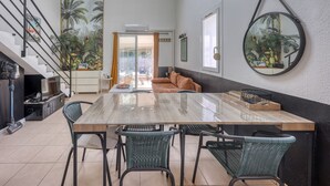 Un comedor con una mesa grande, cuatro sillas, un sofá y una escalera con barandilla.