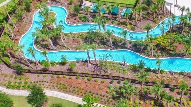 An aerial view of a resort with a winding pool surrounded by palm trees and a fenced area. - Luxury Themed Villa w/ Pool, Game Room, Resort (Davenport)
