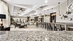 A modern kitchen with granite countertops, a bar area, and a dining space with dark chairs and a patterned rug. - Luxury Themed Villa w/ Pool, Game Room, Resort (Davenport)