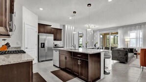 A modern kitchen with a central island, stainless steel appliances, and pendant lighting. - Luxury Themed Villa w/ Pool, Game Room, Resort (Davenport)