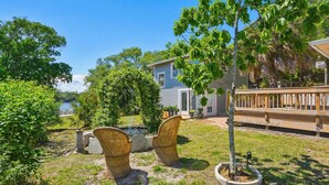 Ein Haus mit Terrasse, ein kleiner Garten mit Korbstühlen und ein Baum.
