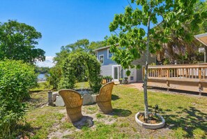 Ein Haus mit Terrasse, ein kleiner Garten mit Korbstühlen und ein Baum.
