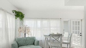 Ein Zimmer mit einem Bett, einem Esstisch mit Stühlen, einer Tür und einer Pflanze.