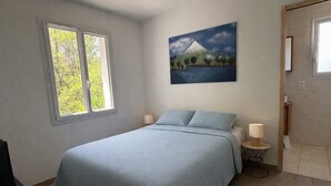 Ett sovrum med en säng, två sänglampor, ett fönster och en tavla på väggen.