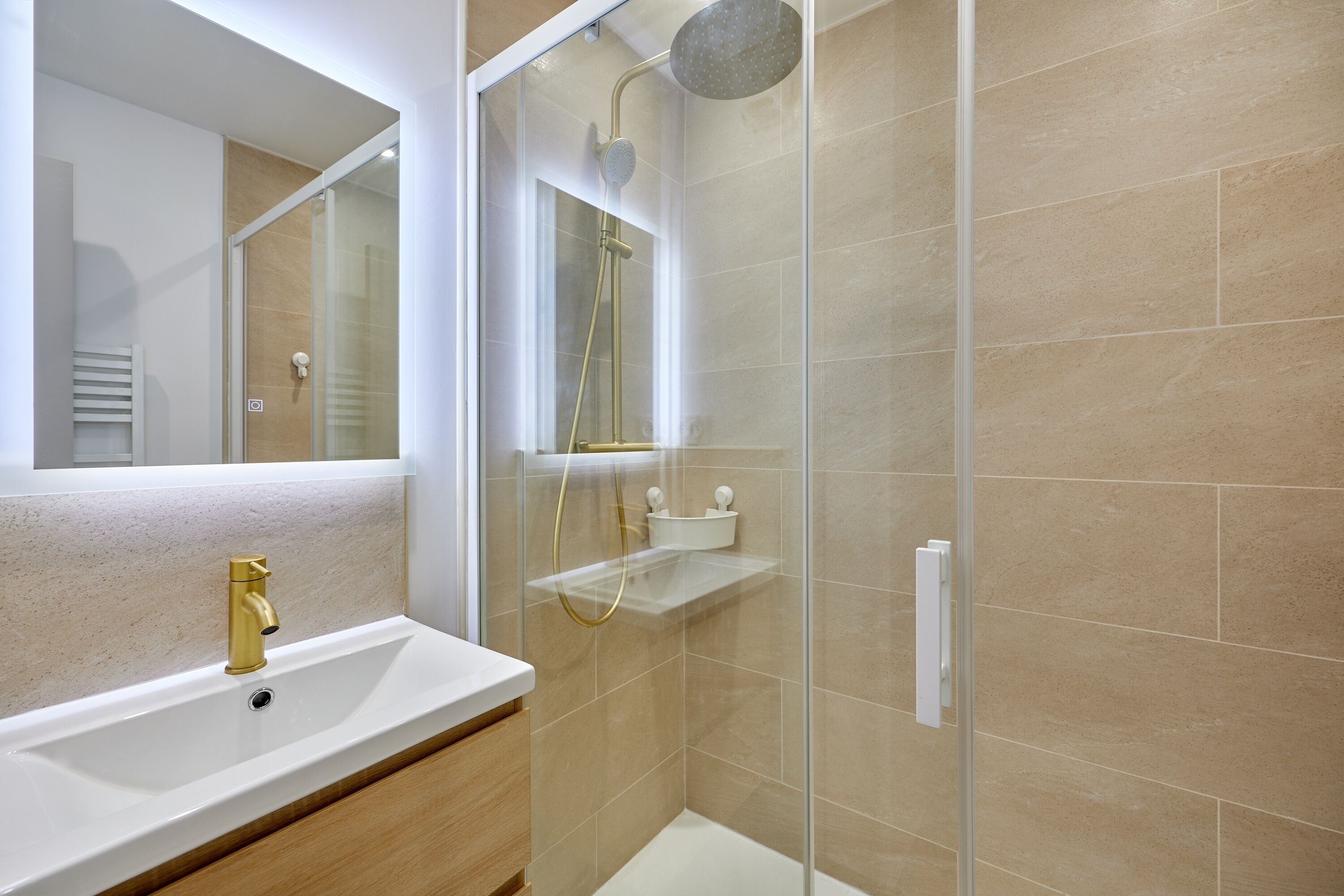 Une salle de bain moderne avec une douche à parois de verre, un lavabo blanc et un miroir.
