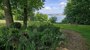 A park with a bench, a lake, and a cityscape in the background. - Le Petit Manoir - Avec Parking privé (Équemauville)