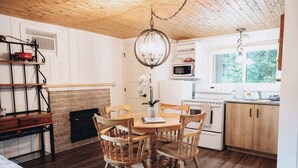 A cozy kitchen with a wooden table, chairs, a hanging light fixture, a microwave, and a stove. - Nature Escape and Miller Zoo | Buddy Shack (Frampton)