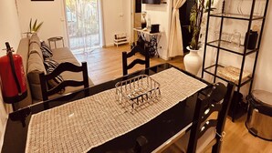 Un comedor con una mesa dispuesta para cuatro, sillas, un extintor, un televisor y una planta.