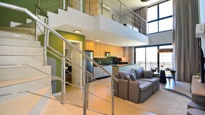 Ein modernes Interieur mit Treppe, einer Couch, einem Essbereich und einer Küche.