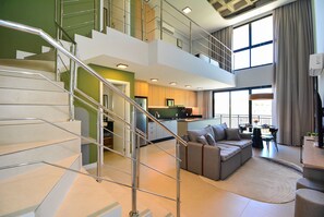 A modern interior with a staircase, a sofa, a dining area, and a kitchen. - Moderno Loft na Lagoa da Conceição  (Florianópolis)