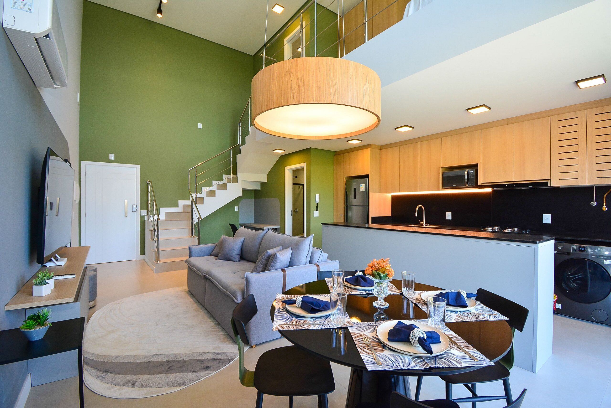 Una cocina moderna con comedor, una escalera y una sala de estar con sofá y mesa de centro.