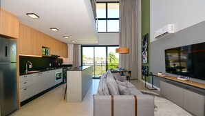 Eine moderne Küche mit integrierten Geräten, eine Essecke mit einer Couch und einem großen Fernseher.