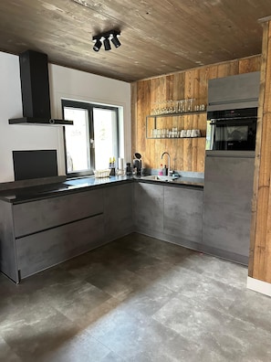 Eine moderne Küche mit einer Holzvertäfelung, einem eingebauten Backofen und einem großen Fenster.