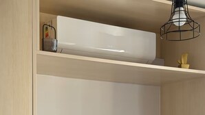 Et moderne værelse med et fladskærms-tv, en loftmonteret aircondition og minimalistisk indretning.