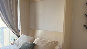 En seng med gavl, et vindue med gardiner og udsigt til det fri.