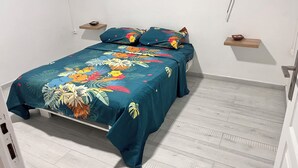A bedroom with a bed, a nightstand, a small shelf, and a window. - Aurore des îles-F3- 2bedroom with jacuzzi and terrace (Le François)