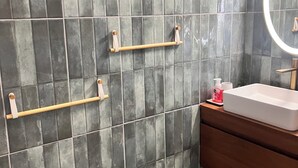 A bathroom with dark grey tiles, a wooden vanity, a white sink, and two towel bars. - Aurore des îles-F3- 2bedroom with jacuzzi and terrace (Le François)