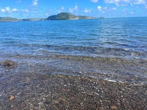 A clear view of a rocky shoreline with calm water and distant landforms. - Aurore des îles—2-bedroom apartment with a jacuzzi and a terrace (Le François)