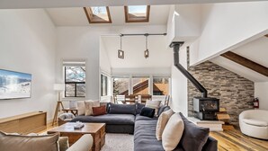 Ein modernes Wohnzimmer mit einer Eckcouch, einem Kamin und Blick auf eine Holztreppe.