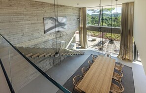 A modern interior with a wooden dining table, chairs, a staircase, and a large window offering a view of greenery. - Indoor Heated Pool with Sauna - Villa L Excelsior (Sveti Donat)