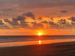 Ein Sonnenuntergang über einem Strand, die Sonne ist in der Nähe des Horizonts zu sehen.
