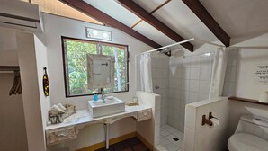 A bathroom with a shower, toilet, sink, and a mirror. - Vrbo Property (Parrita)