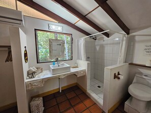 Ein Badezimmer mit Dusche, Toilette, Waschbecken und Spiegel.