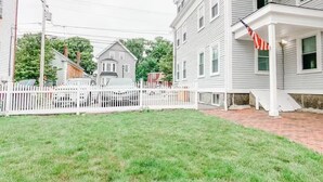 A residential area with a white picket fence, a brick pathway, and a house with a porch.