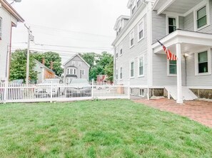 A residential area with a white picket fence, a brick pathway, and a house with a porch.
