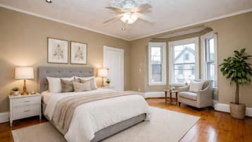 A bedroom with a bed, bedside tables, a chair, a plant, and a window.