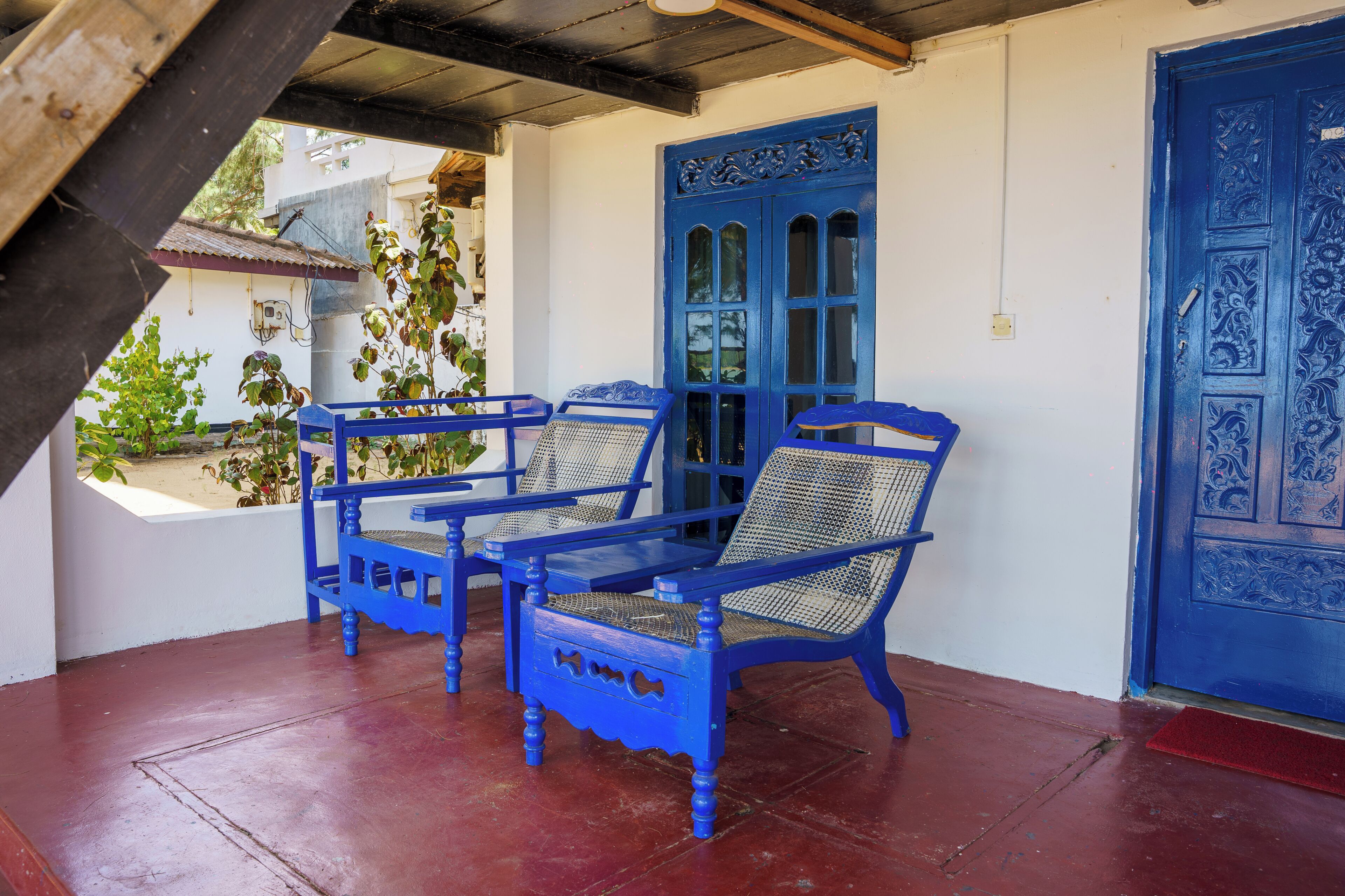 A covered porch with blue furniture and a blue door.