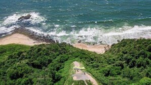 An aerial view of a coastal area with a beach, dense greenery, and a pathway leading to the beach. - Casa cancun hotel boutique e eventos (Penha)