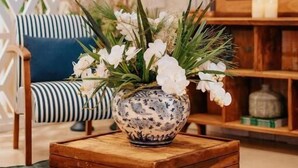 A room with a wooden coffee table, a blue sofa, a decorative vase with flowers, and a wooden cabinet. - Casa cancun hotel boutique e eventos (Penha)