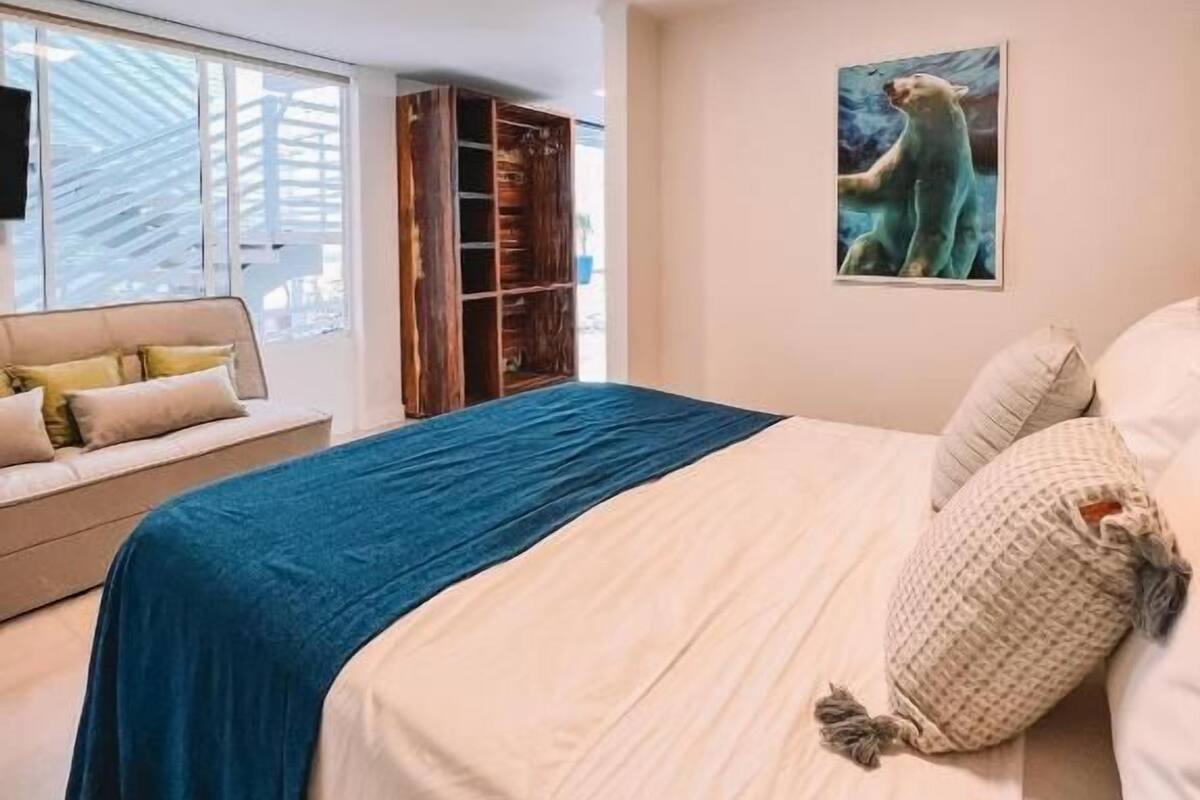 A bedroom with a bed, a blue throw blanket, a polar bear painting, and a built-in wardrobe.