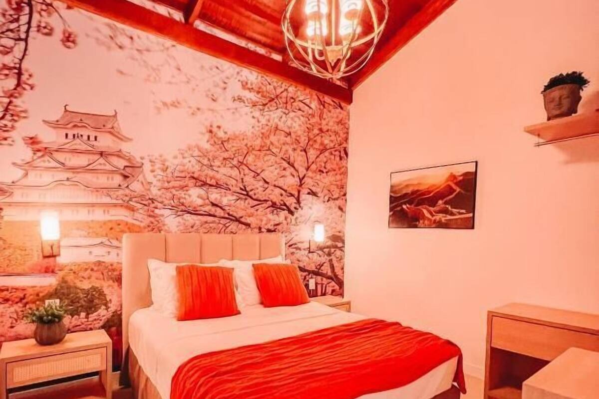 A bedroom with a bed, nightstands, a wall-mounted shelf, and a hanging light fixture.