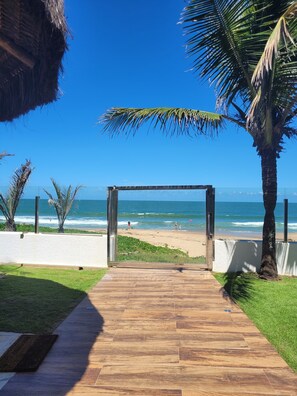 Un sendero de madera que conduce a una playa con palmeras y un cielo azul despejado.