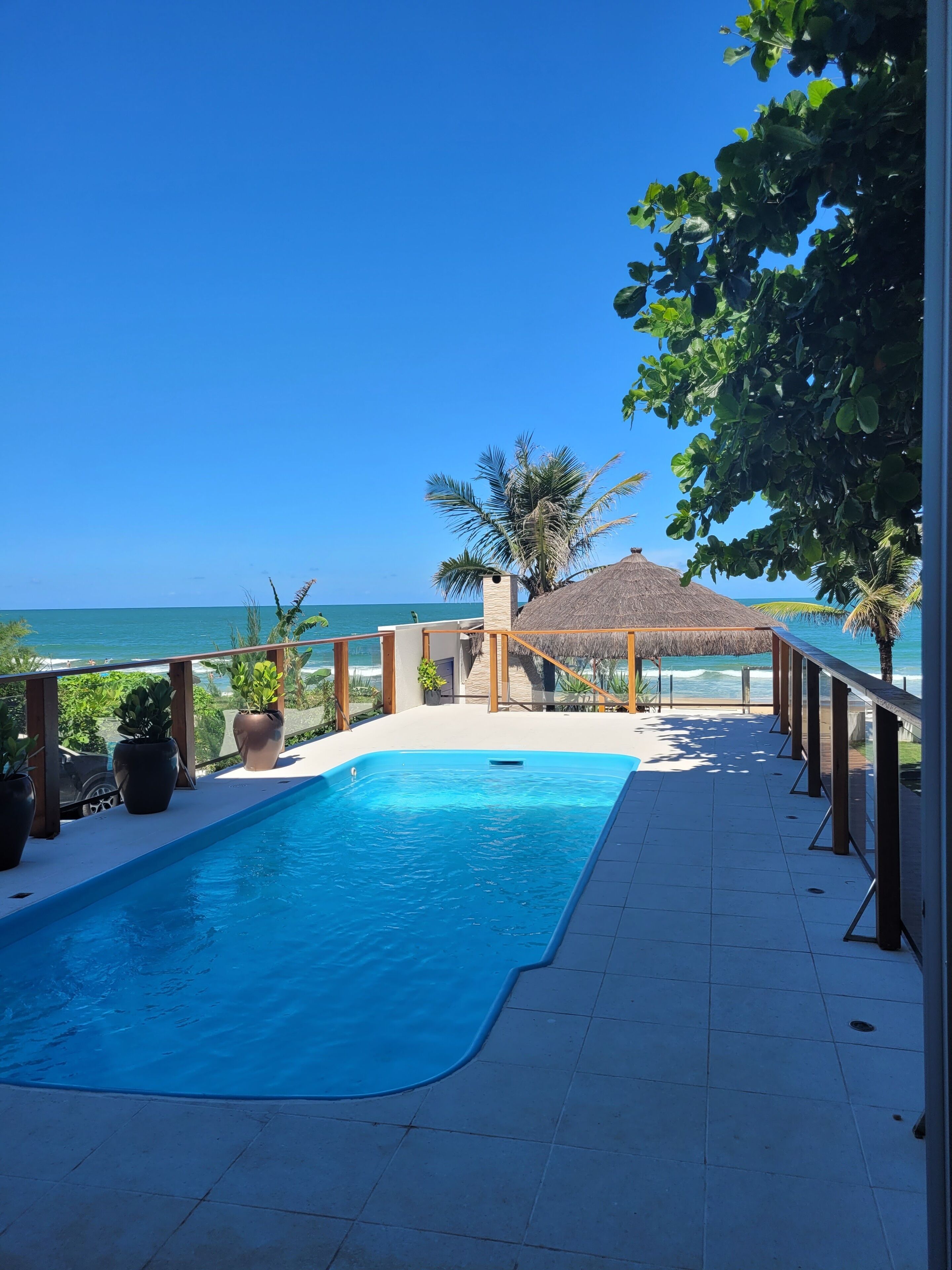 Una piscina con vista al océano, rodeada de macetas con plantas y una terraza de madera.