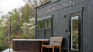 En modern byggnad med stora fönster, en träveranda och en bubbelpool.