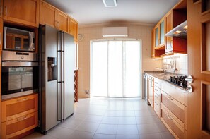 Une cuisine avec des meubles en bois, des appareils électroménagers en acier inoxydable et un sol carrelé.