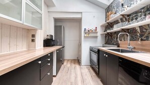 Una cocina moderna con tragaluz, armarios negros, encimeras de madera, horno empotrado y una estantería para vinos.