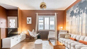 Una sala de estar moderna con un sofá, televisor, sillón, mesa y un cuadro.
