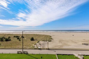 Una playa con valla, camino y zona verde.