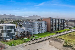 Un edificio residencial de varios pisos con techo plano, balcón y un pequeño jardín.