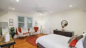A bedroom with a bed, desk, chair, bedside table, and a ceiling fan.